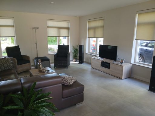 Woonkamer voorzien van mooie rolgordijnen Ruime woonkamer met comfortabele stoelen, televisie en planten. Goede lichtinval.